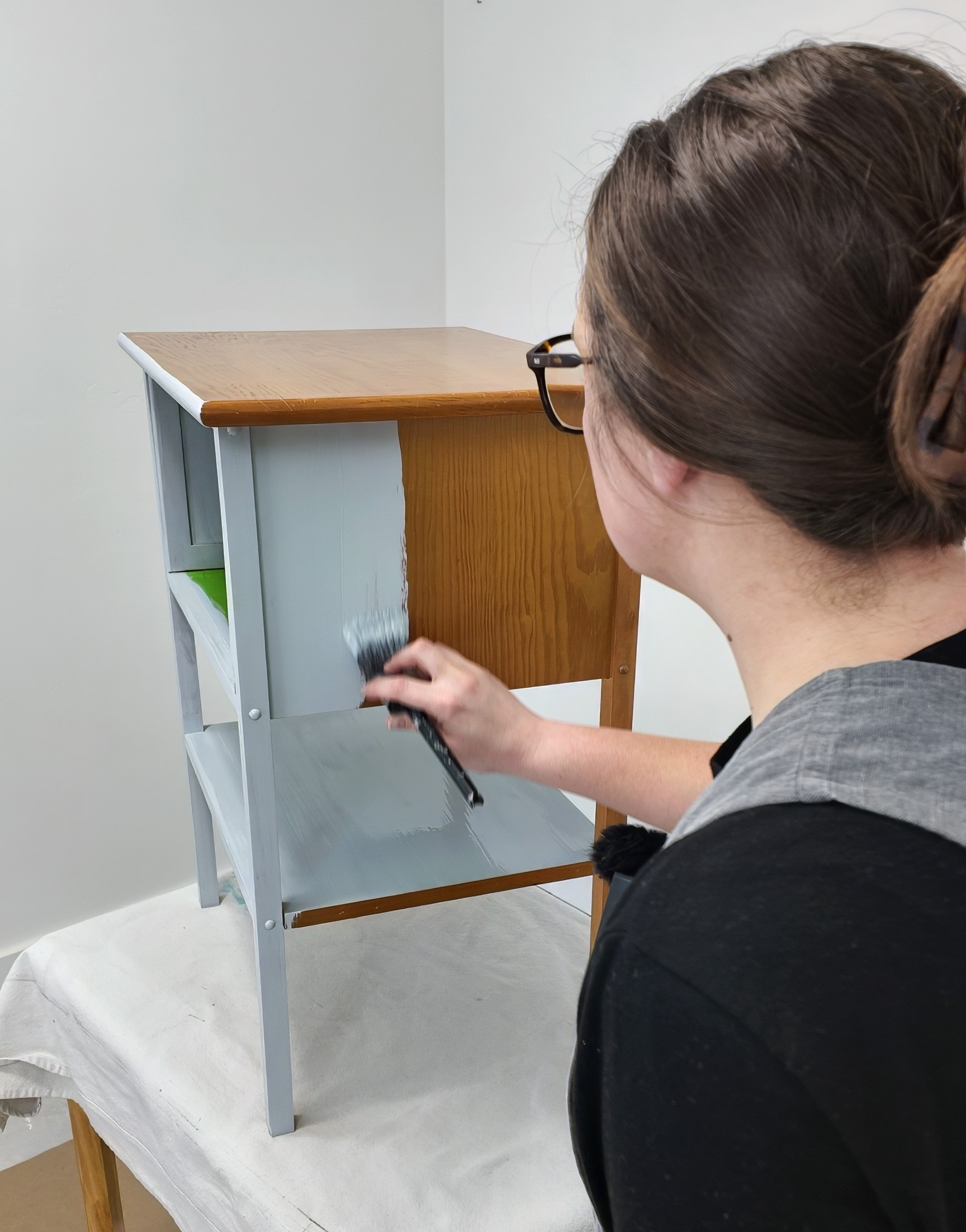 Natalie painting a table light blue with a paint brush